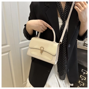 Close-up of cream textured crossbody bag with gold metal buckle and leather strap