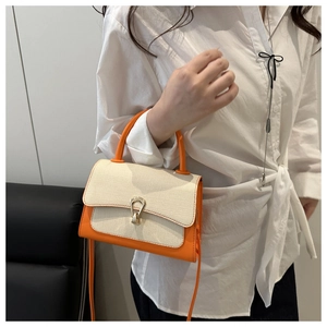 Detailed side view of orange and off-white woven shoulder bag with gold horseshoe buckle