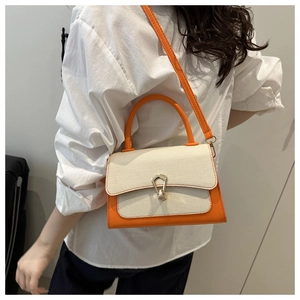 Detail view of the orange and cream paneled small crossbody bag with gold U-shaped lock