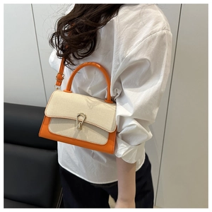 Detail of crossbody bag with orange leather, woven fiber texture and gold hardware