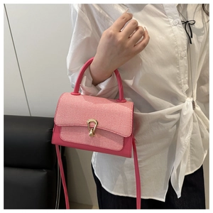 Close-up of pink leather handbag with woven texture and gold horseshoe buckle detail
