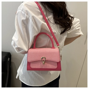 Detail of a pink contrast small square bag with textured weaving and gold horse-bit buckle