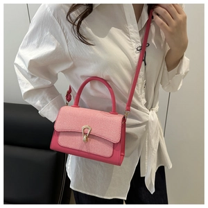 Detailed view of women's pink crossbody bag featuring a woven flap and gold buckle