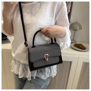 Chic black and textured grey crossbody bag worn by a model in a cozy cafe setting