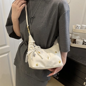 Chic beige leather half-moon shoulder bag with pearl bow and lace charm detail