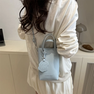 Chic light blue mini crossbody bag with a cute dog charm shown in a lifestyle scene