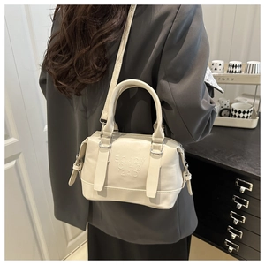 Détail du sac Boston en cuir blanc crème avec logo en relief et bandoulière réglable