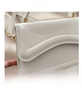 Macro view of white leather bag featuring wave-edge design and fine stitching details