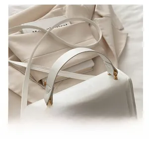 Detail view of white leather square bag with gold metal buckle and fixed top handle