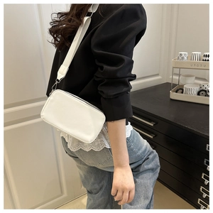 White lychee texture square shoulder bag with wide strap worn by a model in a home setting