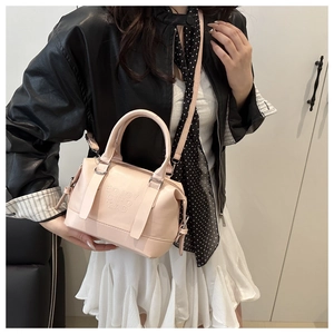 Détail d'un sac Boston rose clair avec logo embossé et poignées rondes élégantes