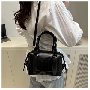 Détail du sac Boston noir brillant avec lettrage embossé et fine bandoulière élégante