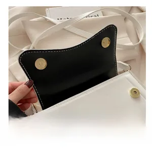 Close-up of premium metal magnetic buckle on trendy black and white crossbody bag