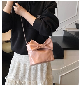 Close-up of pink glossy tote bag featuring a large bow detail and silver chain strap