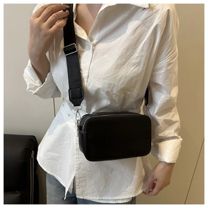 Detail view of black dual-zipper crossbody bag with adjustable wide fabric strap