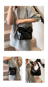 Detail of black patent leather handbag with oversized bow and silver chain strap