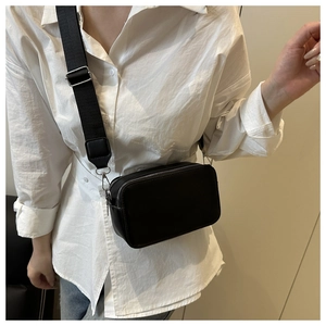 Close-up of a black lychee texture crossbody bag with adjustable wide nylon strap