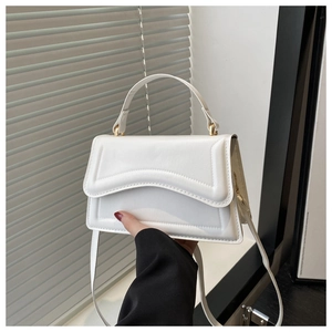 Detail of white PU leather handbag featuring wavy stitched flap and sleek top handle