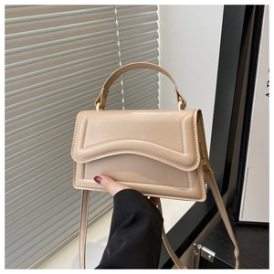 Detail of minimalist beige leather handbag showing wave texture and handle in lifestyle setting