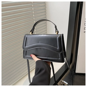Detail of black vintage leather handbag with wave stitching and gold hardware