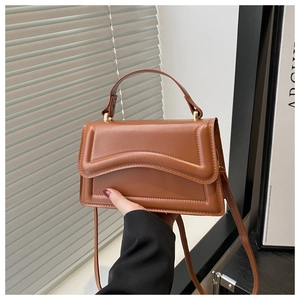 Detail of caramel crossbody bag with unique textured flap and top handle in modern style
