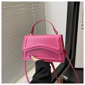 Detail of hot pink handbag with curved quilted design and elegant gold hardware