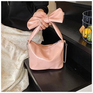 Detail of pink patent leather tote with oversized bow handle and silver chain strap