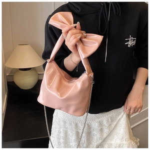 Detail of pink patent leather tote bag with unique bow handle and silver chain strap