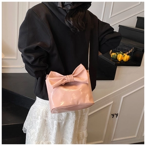 Close-up of pink glossy tote bag featuring a large bow and metallic chain strap