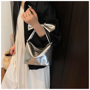 Detail of silver metallic tote bag featuring a large decorative bow and top zipper closure