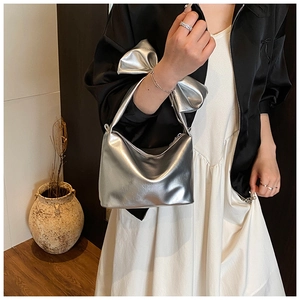 Close-up of metallic silver crescent bag featuring a large decorative 3D bow accent