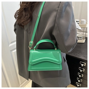 Detail of bright green crossbody bag with unique wavy textured flap and gold hardware