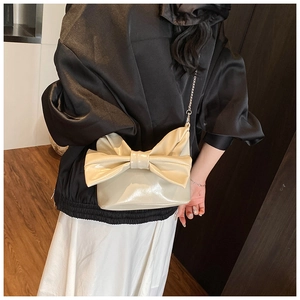 Back view of model wearing a creamy white bow handbag with a silver metal chain strap