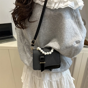 Women's black quilted crossbody bag with pearl handle and golden metallic buckle