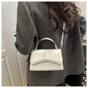 Detail of white leather crossbody bag with geometric folding texture and gold hardware