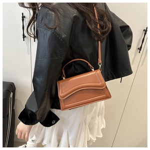 Brown leather crossbody bag with wavy flap detail shown on a model for daily style