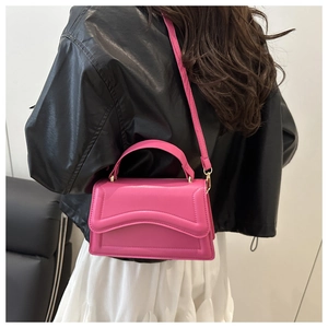 Detailed view of pink quilted handbag with wavy stitching and adjustable strap on a model