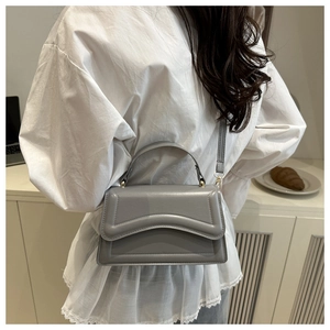 Gray leather crossbody bag with wave stitching detail and curved top handle
