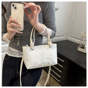 Detail of white lace bucket bag with 3D butterfly embroidery and pearl bead handles