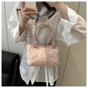 Détail de broderie papillon sur sac à main rose abricot avec texture dentelle
