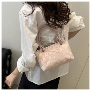 Dettaglio dell'elegante ricamo a farfalla e trama di pizzo su questa borsa rosa