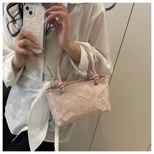 Détail d'un sac à main en dentelle rose avec des appliques florales de papillons en 3D