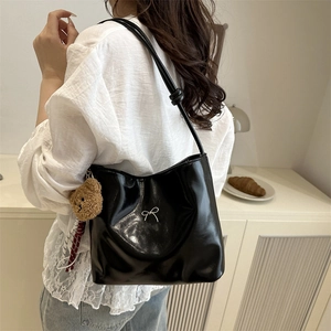 Glossy black leather tote bag with silver bow and plush bear charm for daily commute