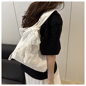 Close-up of white lace tote bag featuring floral embroidery and large bow detail