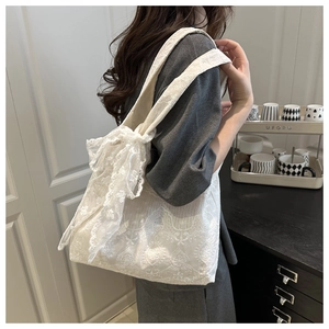 Detail of white lace flower tote bag featuring a large side bow and floral embroidery