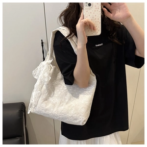 Detailed close-up of white lace floral tote bag with crochet pattern and bow detail