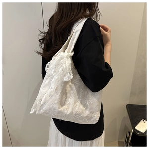 Close-up of white lace tote bag with floral embroidery and large decorative bow detail