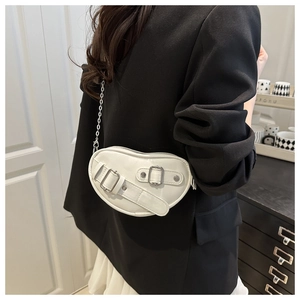 Détail du sac cœur blanc en similicuir avec chaîne argentée sur un blazer noir