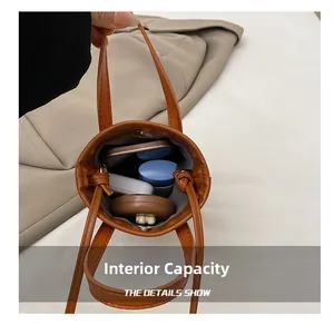 Internal capacity of brown mini bucket bag showing phone, earphones, and makeup