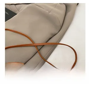 Detail of a thin brown leather shoulder strap on a chic woven crossbody bag